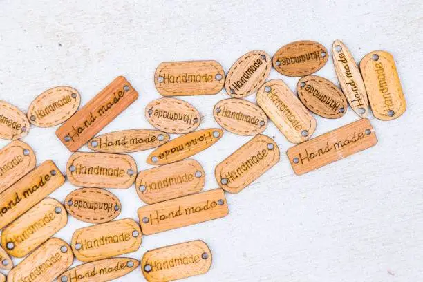 An array of vintage-style wooden tags with the stamped word 'handmade' on a grey background