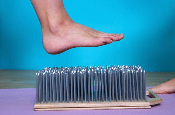 Yogi woman puts her foot on a board with sharp nails
