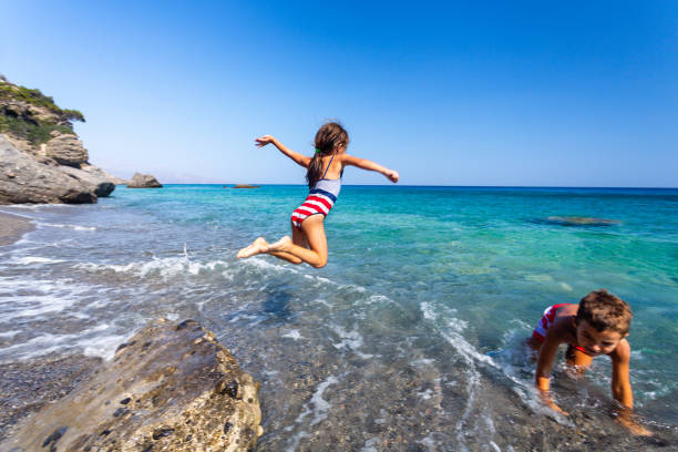 istock Children having fun jumping from a rock 1478025147