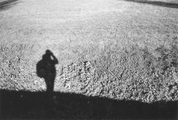 Photographer Silhouette Reflected on the Grass. Milano Outskirts. Film Photography Photographer Silhouette Reflected on the Grass. Chiaravalle, Milano Outskirts, Italy. Film Photography photographic film camera stock pictures, royalty-free photos & images