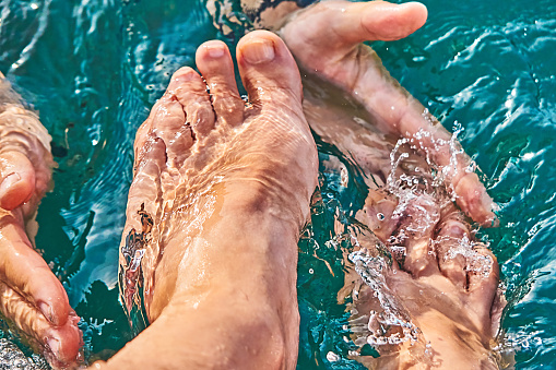 feet and hands in sea water