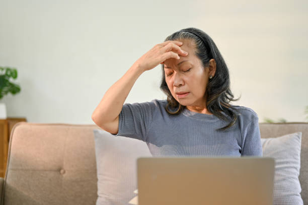 istock Stressed senior Asian woman touching her forehead, suffering from a headache 1478027073