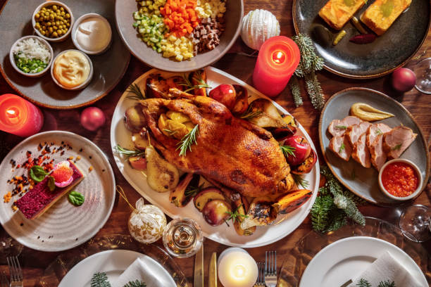istock Festive table setting with fried chicken, pear, rosemary, apples, bacon, mustard, red sauce, spruce branches, olivier salad, mayonnaise, gorka, onion, mayonnaise, sour cream, burning candles, cutlery, champagne glasses and Christmas toys 1478028560