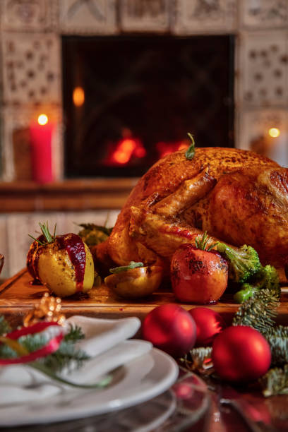 istock Stuffed fried chicken with broccoli, apple, rosemary, walnuts, tomatoes lying on a wooden board surrounded by a festive table, plates, glasses and Christmas tree decorations 1478028592