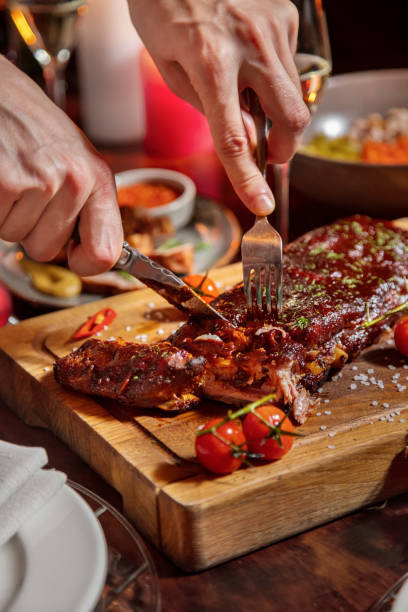 istock A man holds a spoon and a fork in his hands and cuts with them a filial roll with tomatoes and salt which lies on a wooden board and on a festive table 1478028635