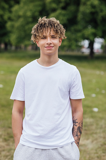 Portrait of a teenage boy standing outdoors looking at the camera smiling. He is at a funfair in Newcastle, North East England.