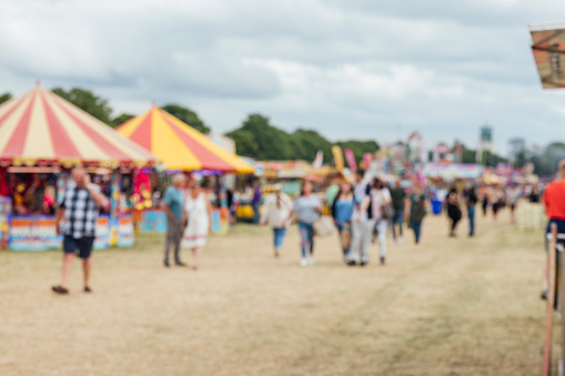 Unfocused shot of a funfair in Newcastle, North East of England. Unrecognisable people are walking through a field with stalls.