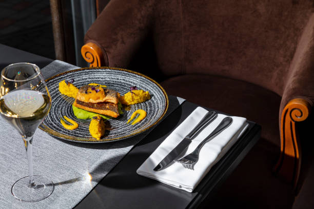 istock Fried fish with mashed potatoes, sprouts, mango, and sauce in a plate on the table with a napkin, cutlery and a glass of wine 1478031143
