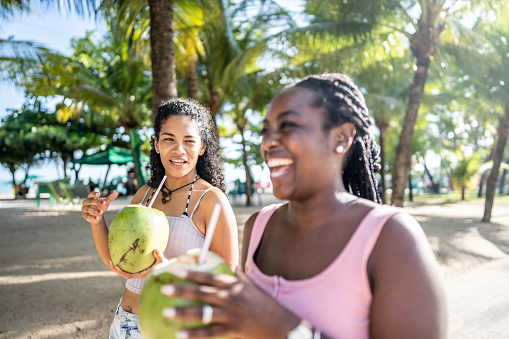 Friends walking in a boardwalk drinking coconut water