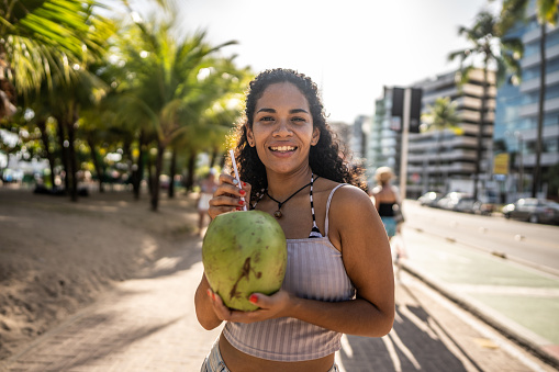 Portrait of a mid adult woman drinking coconut water in a boardwalk