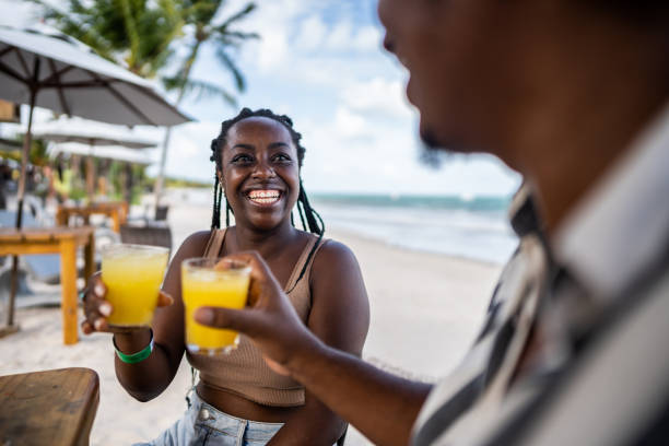 Mid adult couple doing a celebratory toast in a restaurant at the beach Mid adult couple doing a celebratory toast in a restaurant at the beach tourist couple candid travel stock pictures, royalty-free photos & images