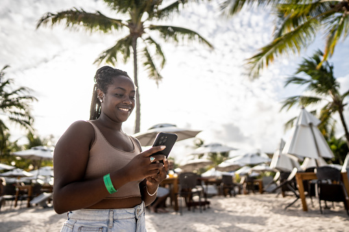 Mid adult woman using smartphone at the beach