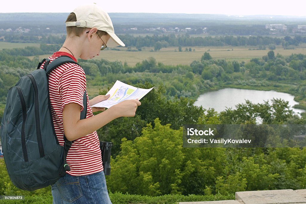 Boy with binoculars, backpack and map Boy with binoculars and backpack looks at the map on a hike Map Stock Photo
