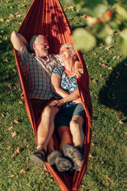 senior couple bonding on the hammock. free time together. positive retired people. senior couple bonding on the hammock. free time together. positive retired people. hammock relaxation women front or back yard stock pictures, royalty-free photos & images
