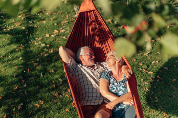 senior couple bonding on the hammock. free time together. positive retired people. senior couple bonding on the hammock. free time together. positive retired people. hammock relaxation women front or back yard stock pictures, royalty-free photos & images