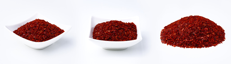 Chili pepper flakes in white bowl, isolated on white background