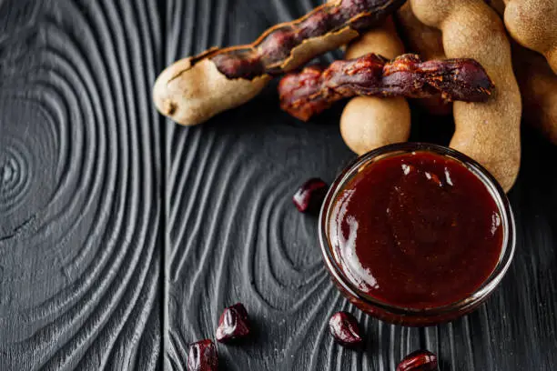 sweet and sour tamarind sauce on a black rustic wooden background.
