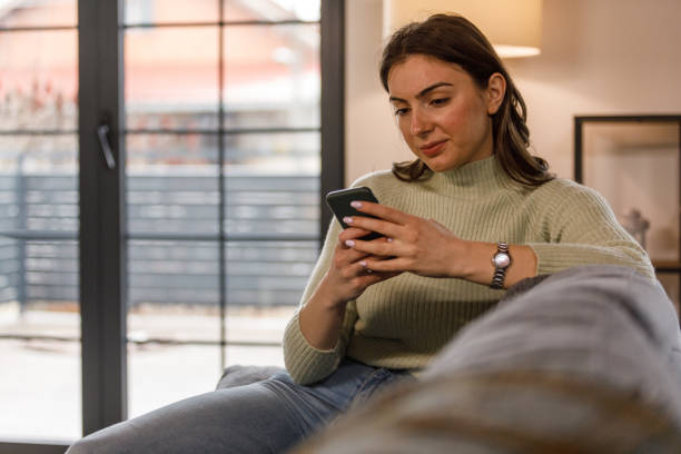 istock Young woman lounging on the sofa and using smart phone 1478059967