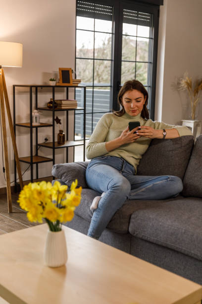 istock Young woman lounging on the sofa and using smart phone 1478060047