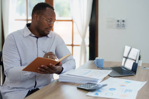 istock middle aged man American African using computer laptop with planning working on financial document, tax, exchange, accounting and Financial advisor 1478060054