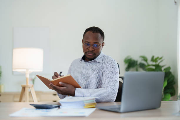 istock middle aged man American African using computer laptop with planning working on financial document, tax, exchange, accounting and Financial advisor 1478060100