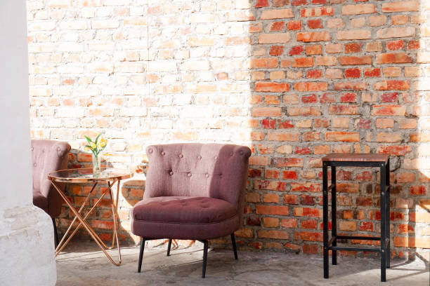 istock A purple chair sits in front of a brick wall with a table 1478060274