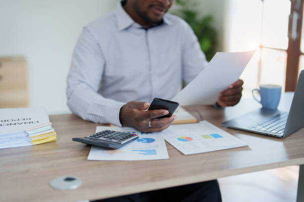 istock middle aged man American African using smart phone mobile and laptop computer with planning working on financial document, tax, exchange, accounting and Financial advisor 1478062333