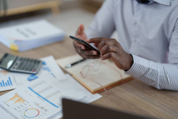 istock middle aged man American African using smart phone mobile and laptop computer with planning working on financial document, tax, exchange, accounting and Financial advisor 1478062507