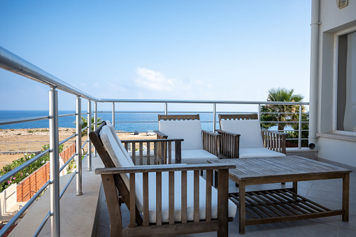 Take a moment to escape the hustle and bustle of everyday life and immerse yourself in the tranquility of this luxurious balcony retreat. The elegant wooden furniture on the balcony invites you to sit back, relax, and enjoy the gentle breeze and the stunning view of the sparkling blue sea in the distance. With its serene ambiance and picturesque setting, this balcony is the perfect place to unwind and recharge. Experience the ultimate luxury retreat on the beautiful island of Cyprus, and let the soothing sound of the waves wash away your worries.