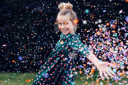 beautiful smiling little girl under a shower of confetti - birthday party carefree celebration concept
