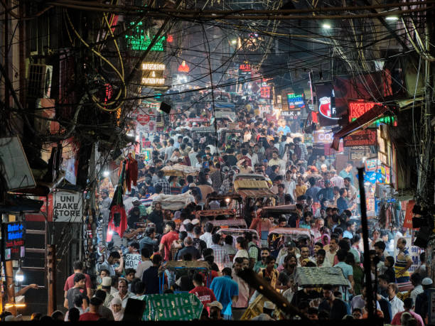 New Delhi, India - 25 Sept 2022: Bustling crowded street of Matia Mahal Road near Jama Masjid at night during weekend. The road is lined with people and vehicles jostling for a space.