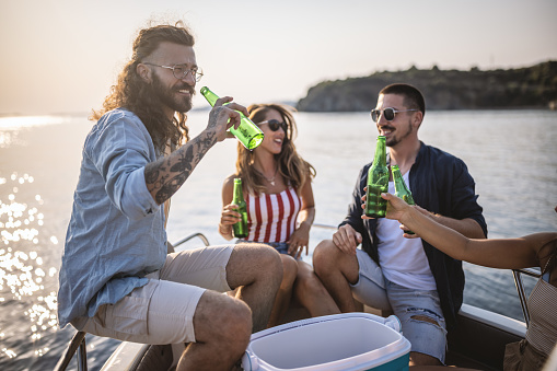 Photo of friends taking a boat trip during summer vacation, they relax and enjoy drinks.