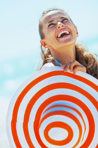 happy young woman in swimsuit with beach hat looking up on copy space