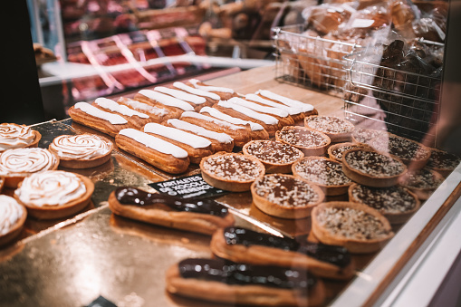 a display case filled with lots of different types of cakes and pies on display in a bakery or deli or bakery shop front view of cakes and frosted with frosting on the shelves. Selective Focus. High quality photo