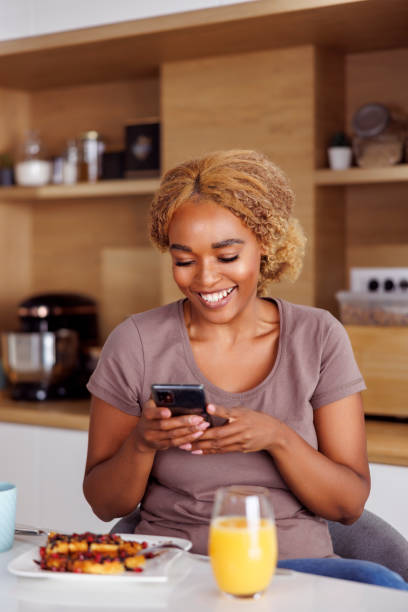 istock Woman using smart phone while eating breakfast at home 1478083875