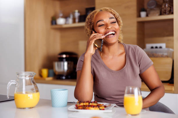istock Woman having phone conversation while eating breakfast at home 1478084441