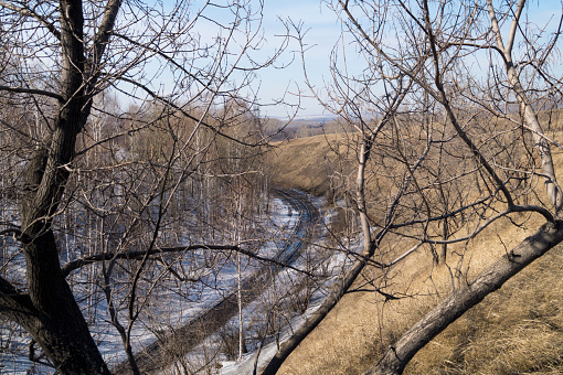 A single-track railway in winter among trees and hills.Winter.