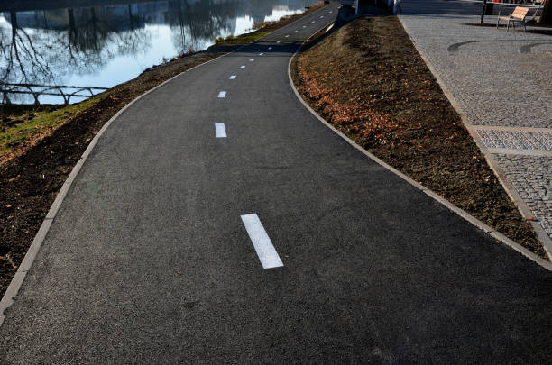 terraplén con un nuevo carril bici justo al lado de los meandros del río. copia su flujo y anima a los ciclistas a continuar a lo largo del agua, banco del parque - concrete curve highway symbol fotografías e imágenes de stock