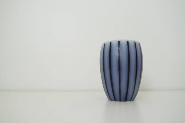 istock Scented candle on a white surface with a white background behind. Gray striped candle or vase. 1478093381
