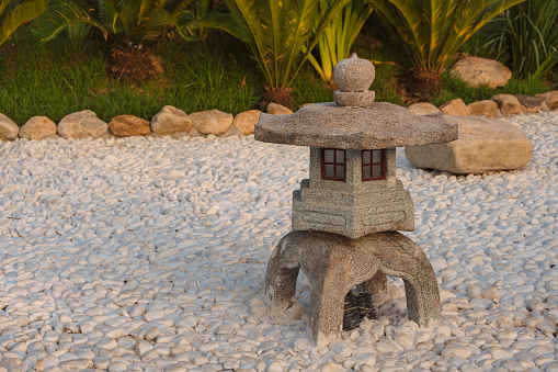 Traditional japanese stone lantern in japanese rock garden with white stones.