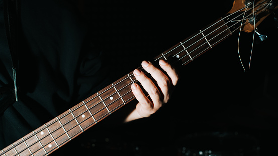 Full length shot of a bearded male artist in a suit playing a plugged electric guitar isolated on white background