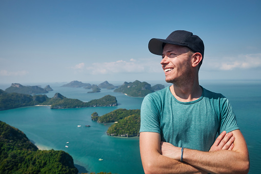 Portrait of laughing man on hill against group of tropical islands in sea, Thailand