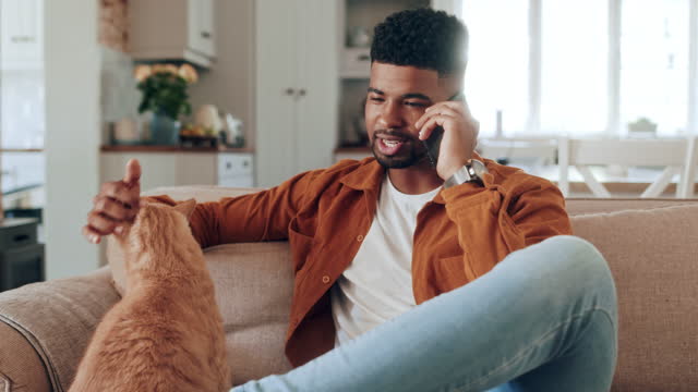 Happy millennial hipster African American businessman sitting on a sofa talking on the phone