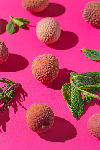 Creative composition made of lychee fruits, mint leaves and green rosemary on bright pink background. Summer refreshment concept. Vitamin healthy food