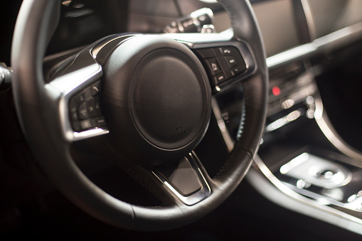Interior of a modern car, close-up on steering wheel.