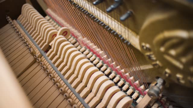 Several piano hammers strike piano strings in an old home piano upright piano made of light wood