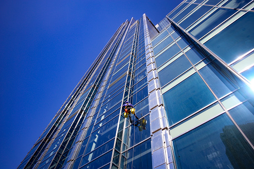 Unrecognizable worker working as a window cleaner on a modern high rise building.