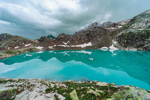 Turquoise colored mountain lake with snow