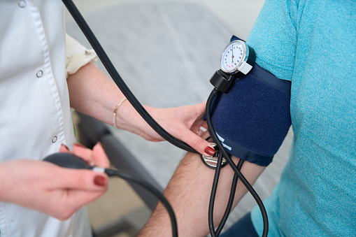 Close up of doctor checking man patient arterial blood pressure. Medical and health care concept