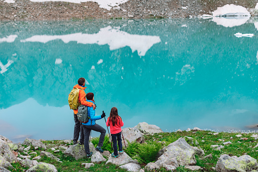 Family with little girl trekking around mountain lake